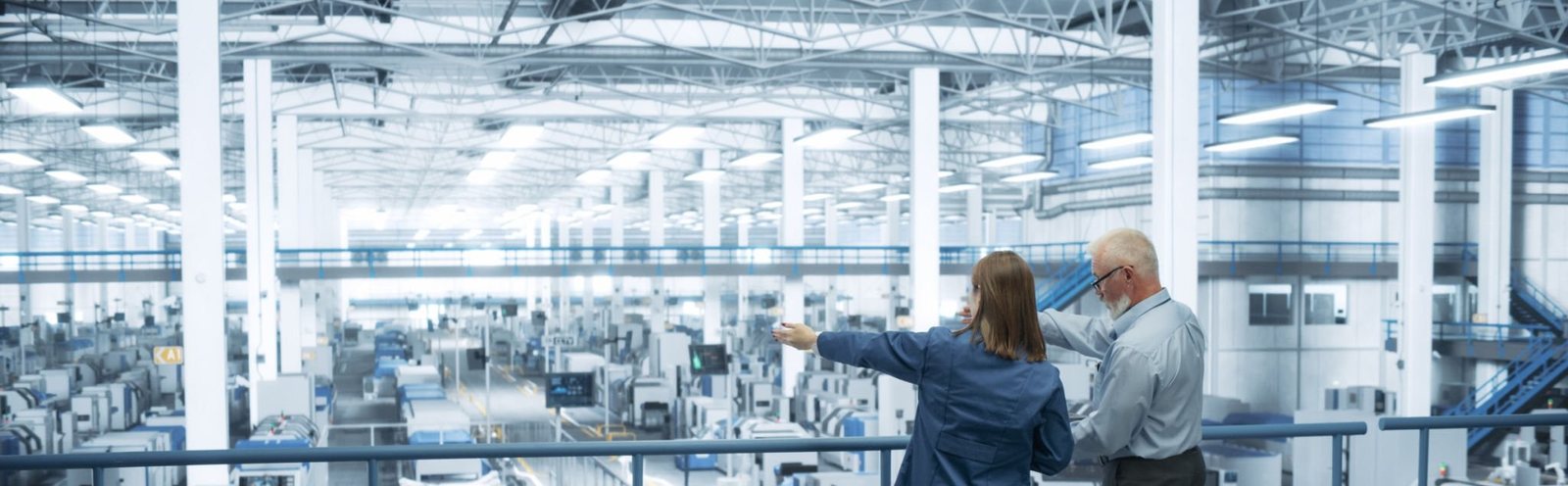 Two colleagues reviewing operations across a manufacturing floor